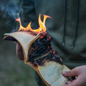 crop faceless man with burning book in hands