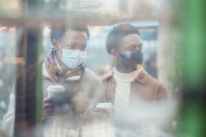 through glass of black gays in medical masks standing near showcase