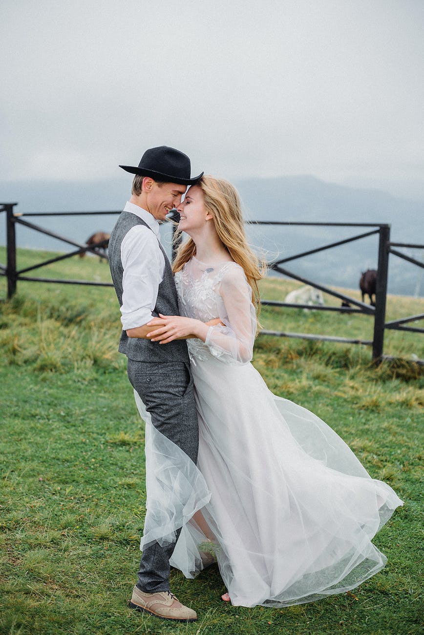 stylish young newlyweds cuddling and smiling in mountainous countryside